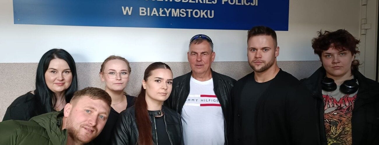 Studenci pozujący pod tablicą Komendy Wojewódzkiej Policji w Białymstoku.