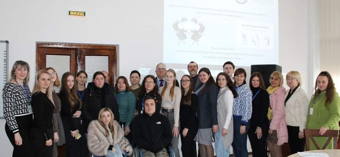 Uczestnicy spotkania z okazji Światowego Dnia Pracy Socjalnej pozujący w sali.