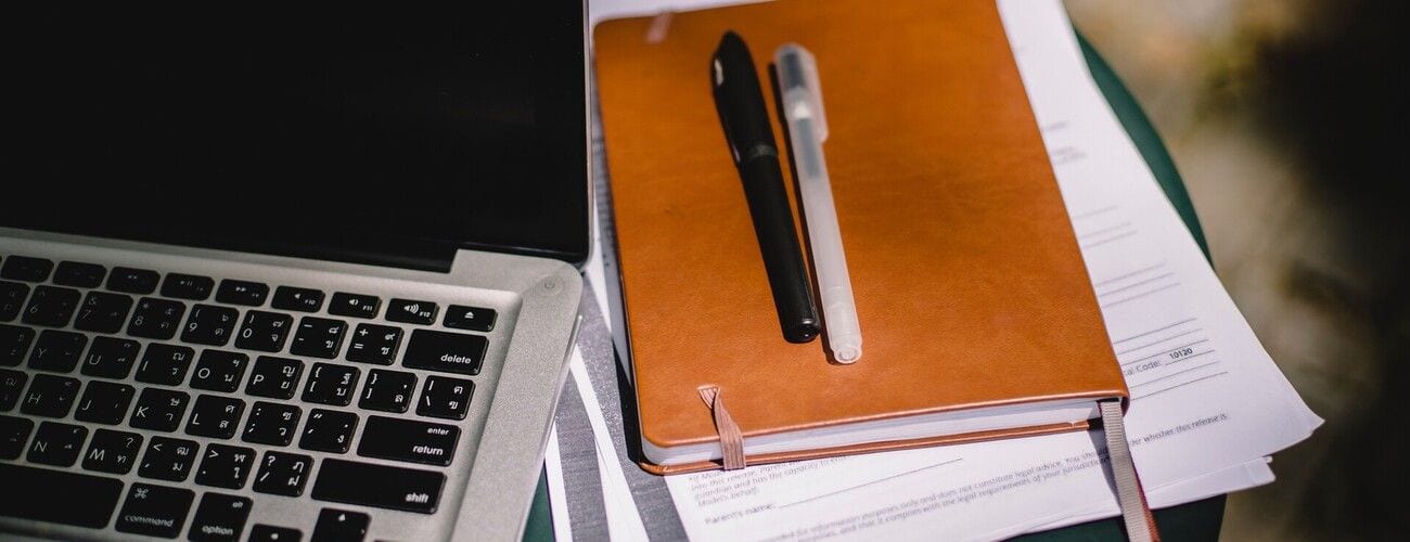 Laptop, notes i długopisy na biurku.