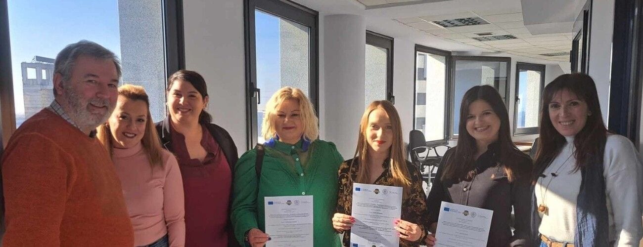 Uczestnicy wizyty przygotowawczej pozujący z dokumentami w jasnym pomieszczeniu.