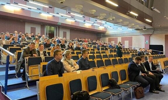 Uczestnicy siedzący w rzędach foteli w auli konferencyjnej.