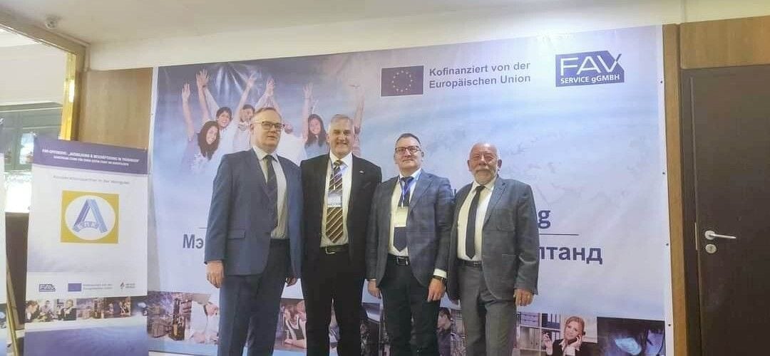Czterej uczestnicy konferencji w Ułan Bator na tle planszy partnerów i oznaczeń Unii Europejskiej.
