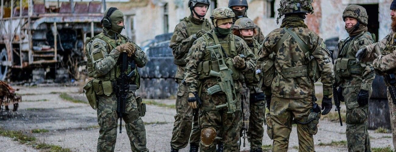 Grupa żołnierzy w umundurowaniu i wyposażeniu polowym podczas ćwiczeń.