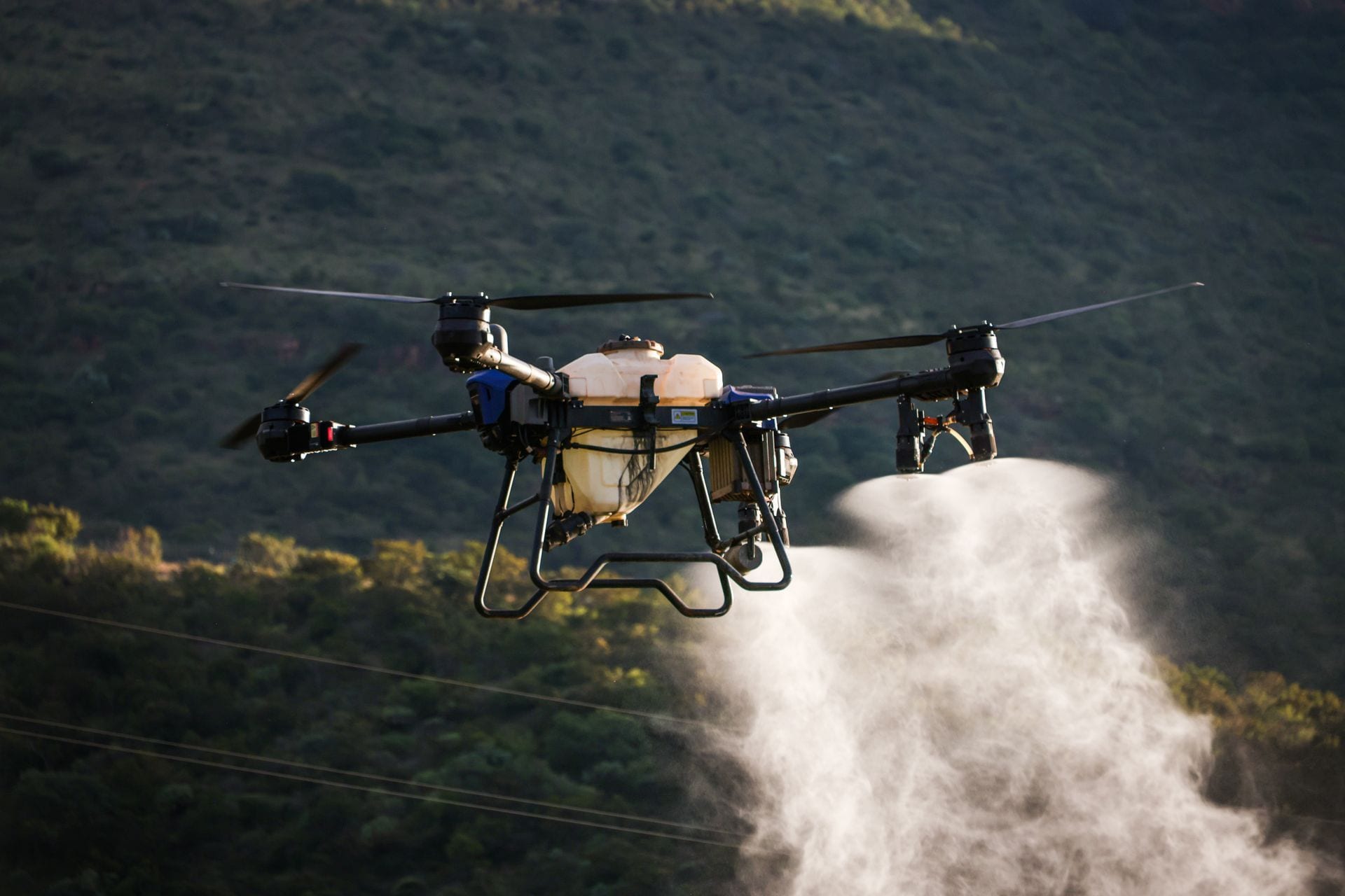 Dron rolniczy opryskujący uprawę na polu