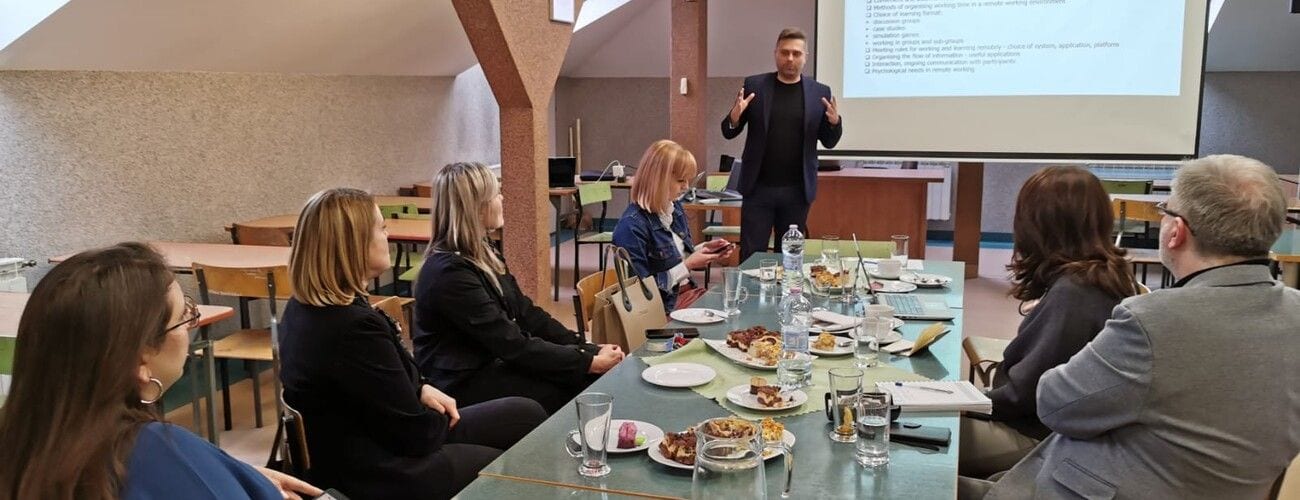 Prelegent przy ekranie i uczestnicy spotkania VETourismINT przy wspólnym stole.