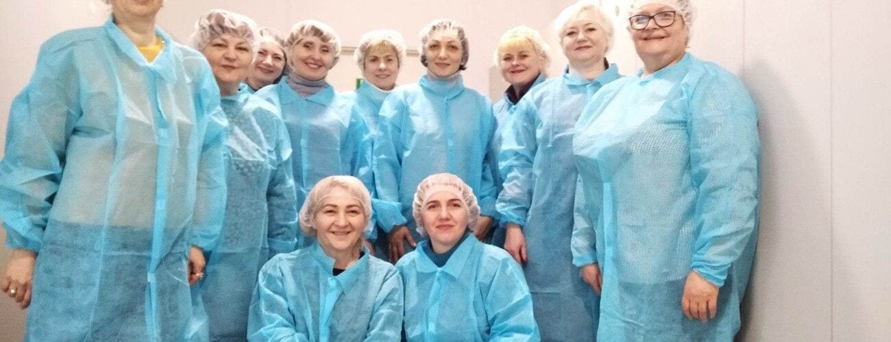 Uczestniczki stażu pozujące w niebieskich fartuchach i czepkach ochronnych.