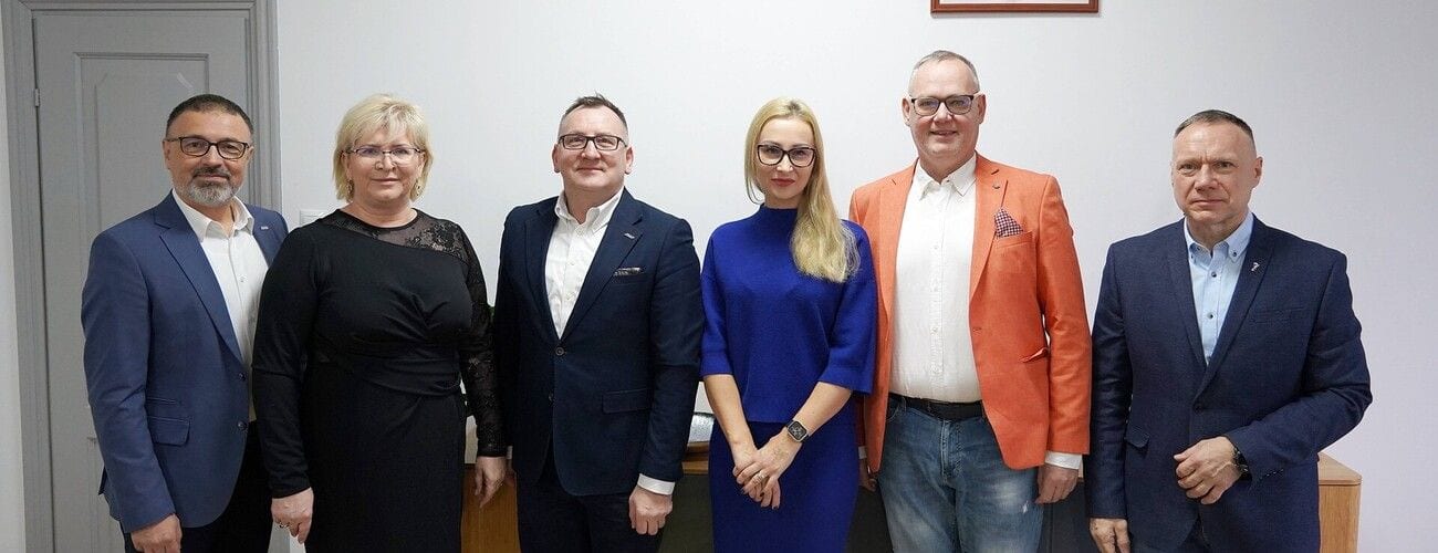 Przedstawiciele współpracujących uczelni pozujący do wspólnego zdjęcia w gabinecie.