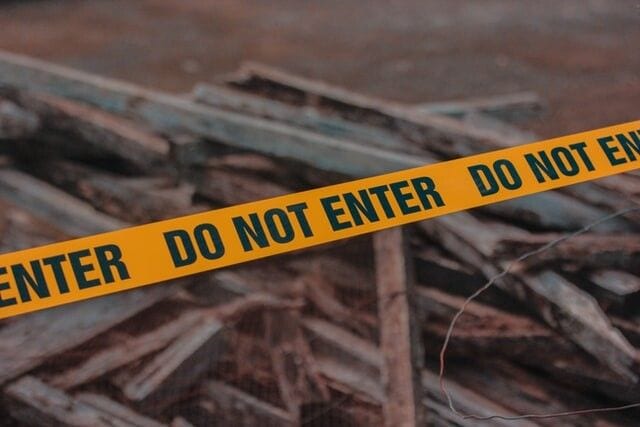 Żółta taśma z napisem „Do not enter” odgradzająca teren.