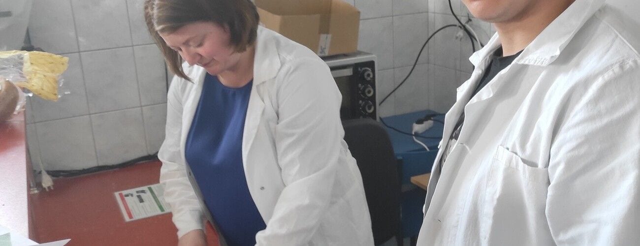 Uczestniczki warsztatów przetwórstwa żywności pracujące w białych fartuchach w laboratorium.