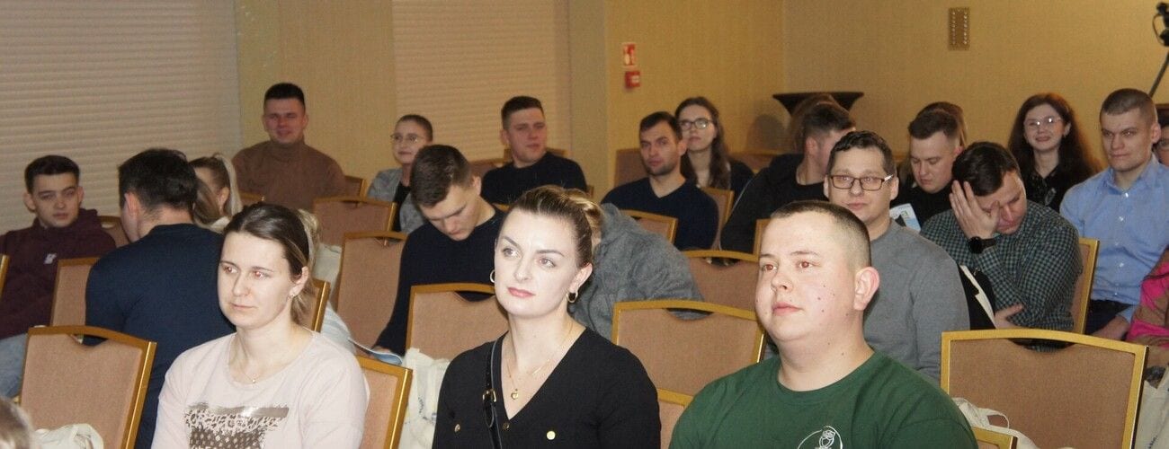 Studenci siedzący w rzędach na widowni podczas konferencji.