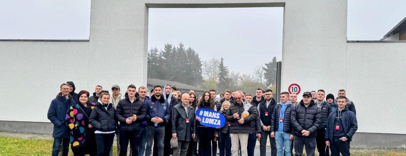 Grupa studentów przed budynkiem zakładu, z tabliczką MANS w Łomży.