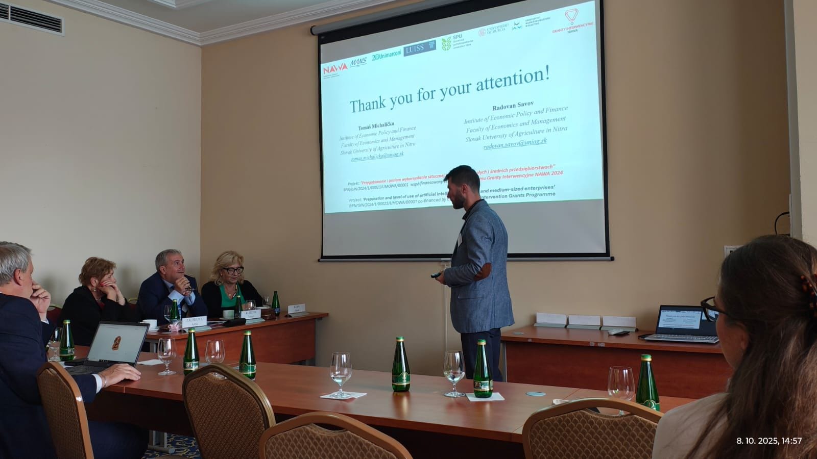 Osoba prowadząca prezentację i uczestnicy spotkania w sali konferencyjnej.