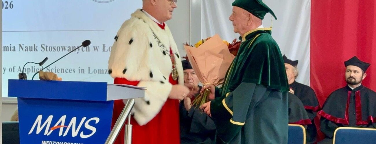 Wręczenie kwiatów osobie w stroju akademickim podczas inauguracji, przy mównicy MANS.