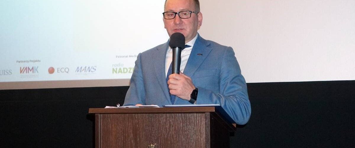 Prelegent z mikrofonem przy mównicy na tle planszy z logotypami partnerów innCREA.