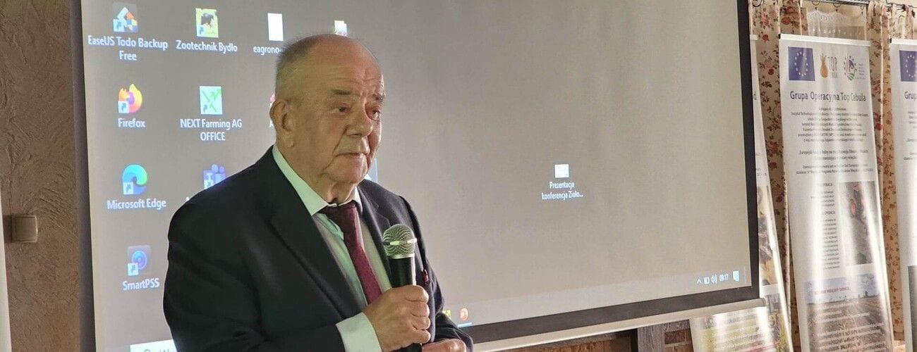Prelegent z mikrofonem przed ekranem podczas konferencji dotyczącej rolnictwa.