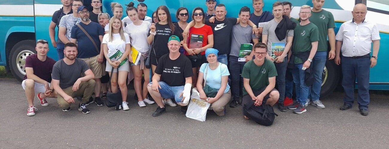 Uczestnicy zajęć terenowych pozujący do wspólnego zdjęcia przed autokarem.